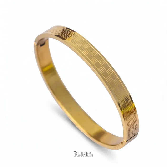 A gold-plated stainless steel bangle bracelet with a textured geometric pattern on the outer band, shown on a white background with a subtle shadow.
